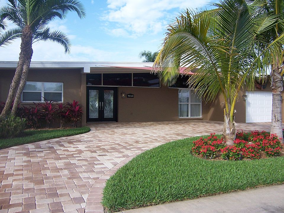 Great curb appeal with brick pavers, mature palms, and custom entryway