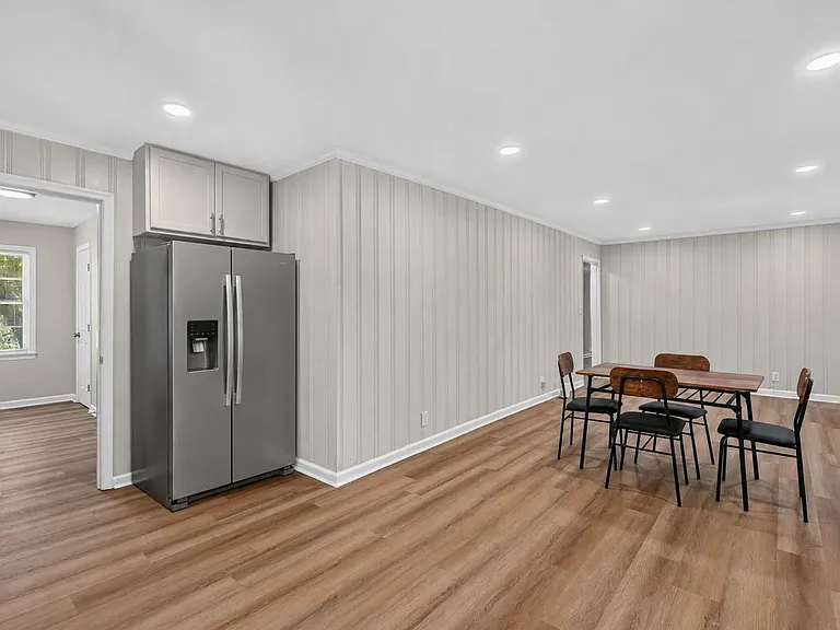 Open dining area with recessed lighting, durable wood-look floors, and space for a full table near the kitchen.