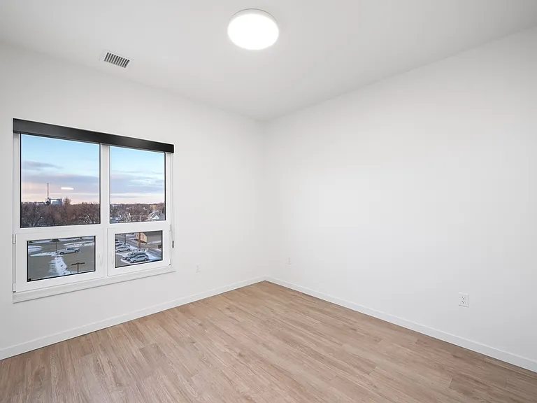 Bright modern room with large window and sleek hardwood floors offering a serene outdoor view. Bright modern room with large window and sleek hardwood floors offering a serene outdoor view.