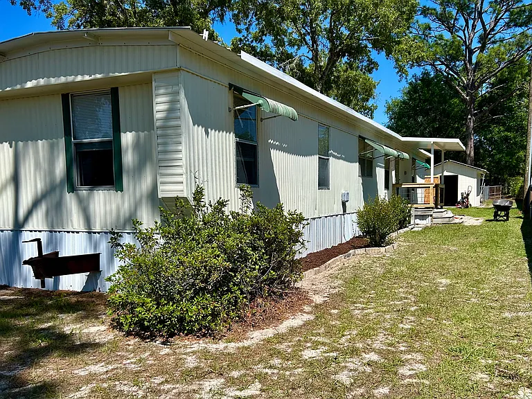 Back of mobile home with porch and big shed