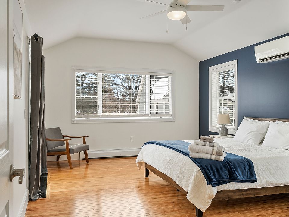 Bedroom, Vaulted Ceiling, Accent Wall, Hardwood Floors, Mini-Split AC, Ceiling Fan, Large Windows, Armchair, En-suite Access.