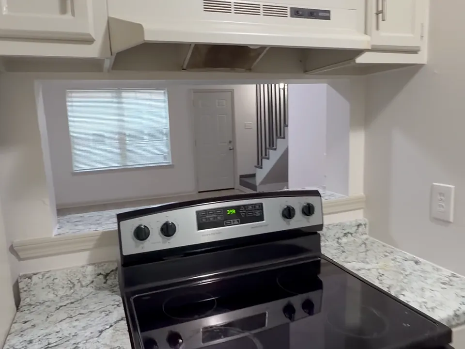 Kitchen includes an electric range, vent hood, and plenty of cabinet space - clean, bright, and functional for everyday cooking.