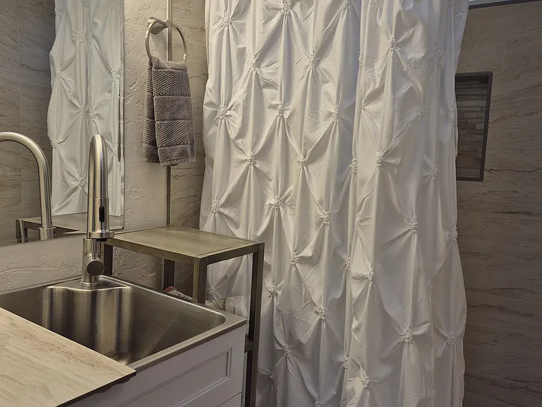 This spacious shower has an eclectic river rock basin and decorative tiling. New sink... new vanity.