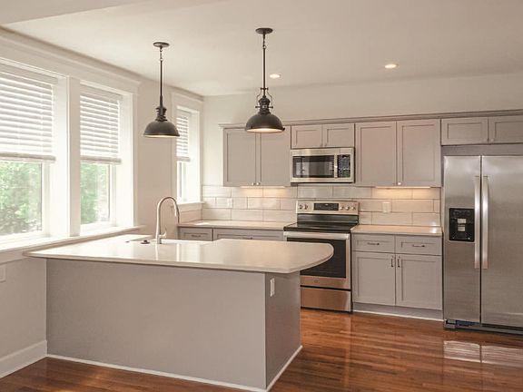 Kitchen with farms sink, bar seating, and new stainless steel appliances.