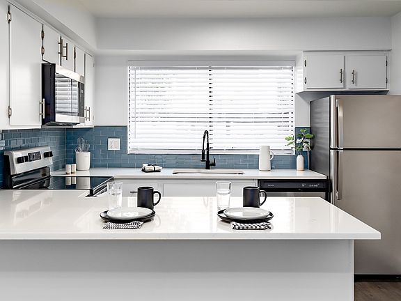 Our 1st floor 2 bedroom apartment kitchens feature white cabinetry, quartz counters, and glass tile backsplashes.
