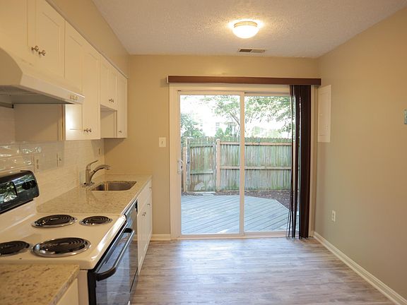 View of the eat-in kitchen and backyard from the dining room. Not in this picture are a kitchen pantry to the left of the camera lens, and to the right, more kitchen cabinets and a refrigerator.