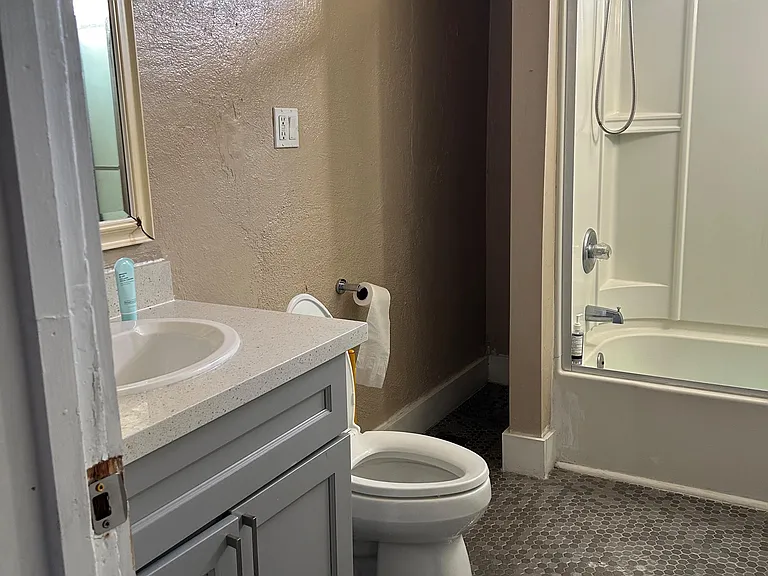 Full bath with vanity storage, toilet, and tub/shower combo, plus a window for natural light and ventilation.