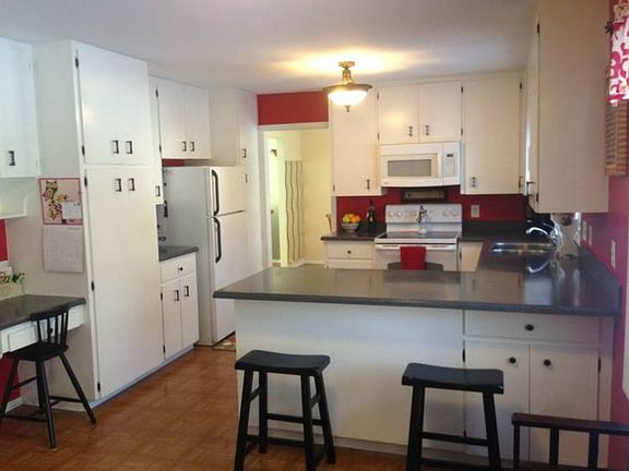 Sparkling white cabinets with new counter top and sink.  Extended counter top with bar stools.  
