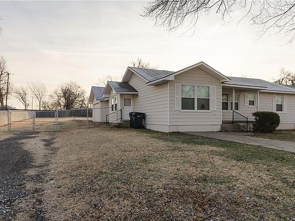 A good view of the side porch and the two car attached garage.  You can see what a large yard it is - stretching all the way back to the fence.  Just over a third of an acre. New chain link fence across the drive.