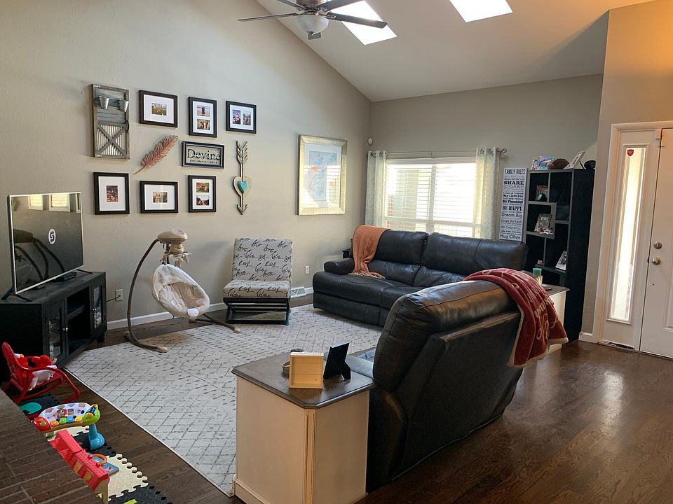 Living room with hardwood floors, skylights, vaulted ceilings and large windows.