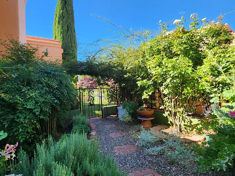 The backyard is a delightful, walled garden full of flowering plants, and provides both a covered sitting area and lovely strolling path.