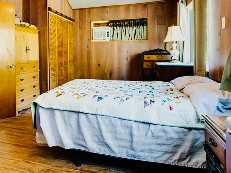 Bedroom has an air conditioner and closet. Large window faces the mountains on Hwy 2.