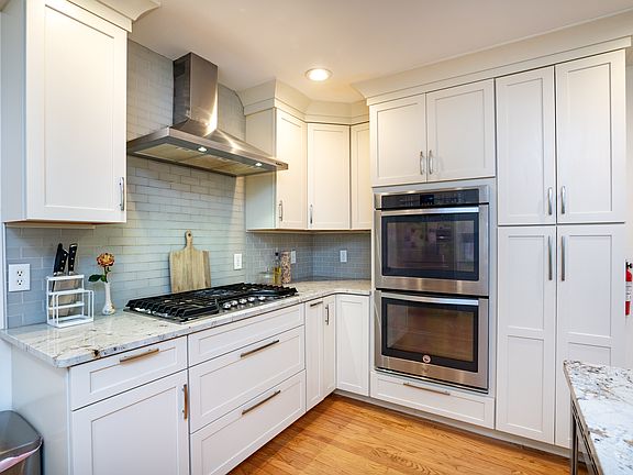 Beautifully updated kitchen boasting dual ovens, a gas range with a stainless hood, granite countertops, ample cabinet space, a breakfast nook, and an island with room for seating.
