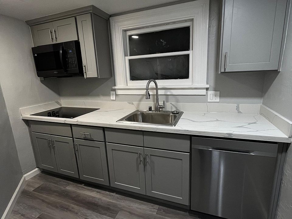 Modern kitchen with an electric cooking range, dishwasher, refrigerator and a built-in microwave.