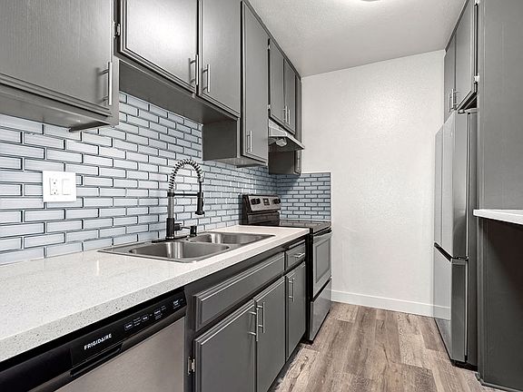 White tiled kitchen with stainless steel fridge, microwave, and oven.