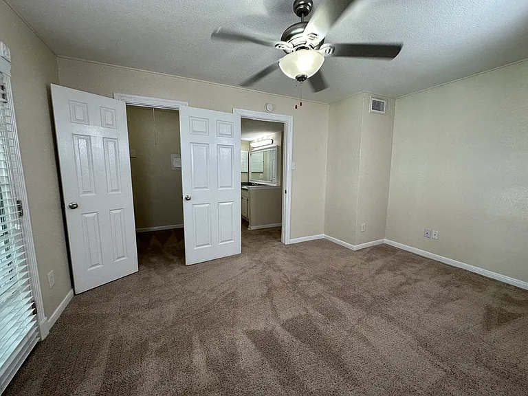 Inviting bedroom with plush carpeting, mirrored closet doors, and modern ceiling fan, offering comfort and style. Inviting bedroom with plush carpeting, mirrored closet doors, and modern ceiling fan, offering comfort and style.