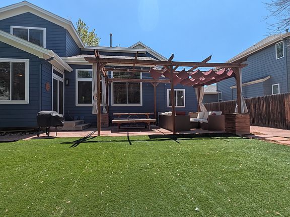 Patio with pergola and retractable wave shade, and zero-maintenance artificial grass.