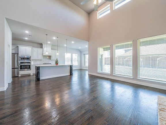 Living room featuring ceiling fan, dark hardwood / wood-style floors, and a high ceiling
