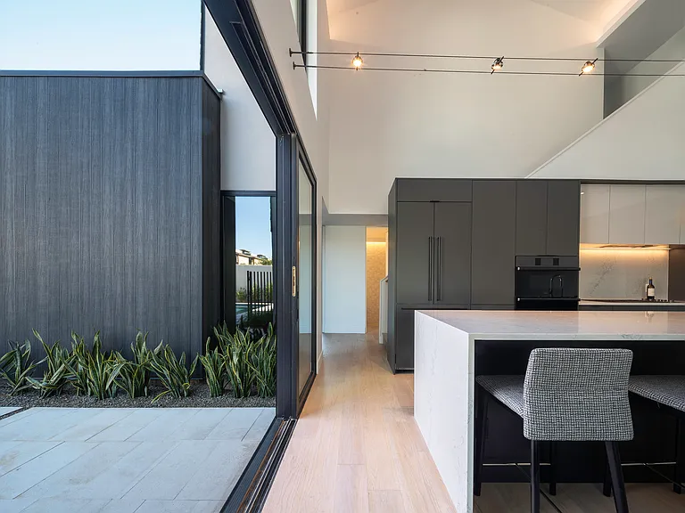 Expansive glass openings connect the kitchen and living spaces to private outdoor courtyards, creating effortless indoor/outdoor Phoenix living.