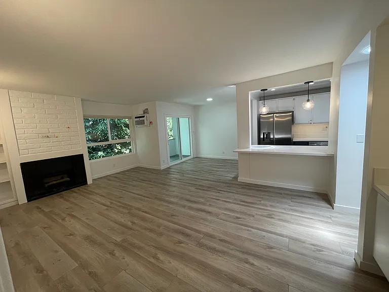 Large living room off kitchen with sliding door leading to a balcony off kitchen and dining area.