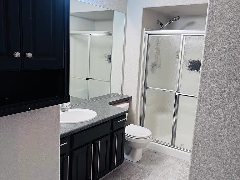 Bathroom with walk-in shower, pocket-door access to Bedroom 1, and a separate entrance from the main apartment
