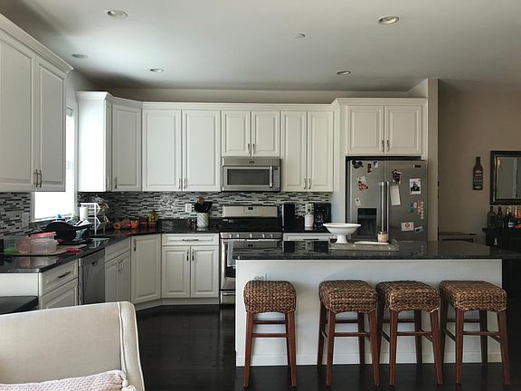 Gorgeous open modern kitchen with island, stainless steel appliances, granite countertops & trendy tiled backsplash