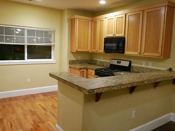 Kitchen with hardwood floor, granite countertop, gas stove and plenty of cabinets spaces