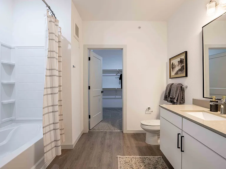 The secondary bathroom in this Garrett Parker B1 floor plan includes a tub and shower combo, a single sink vanity, and a nearby closet.