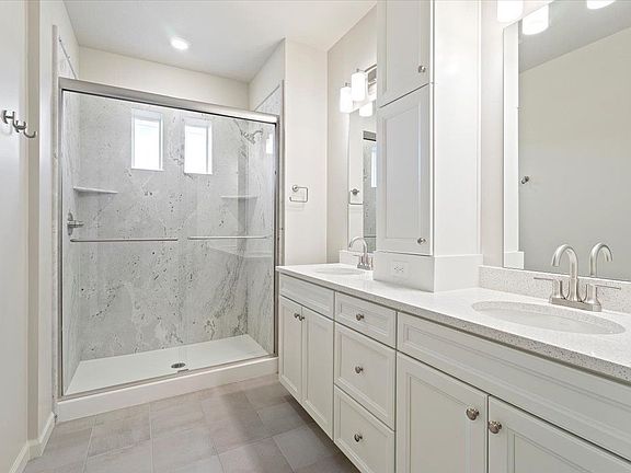 A view of the primary bathroom vanity and walk-in shower
