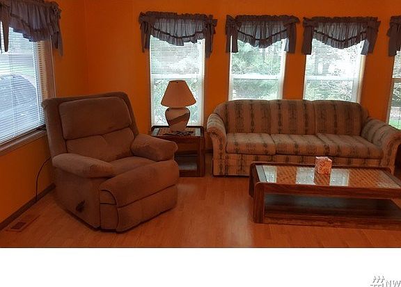 Living room with wood laminate flooring and propane stove.
