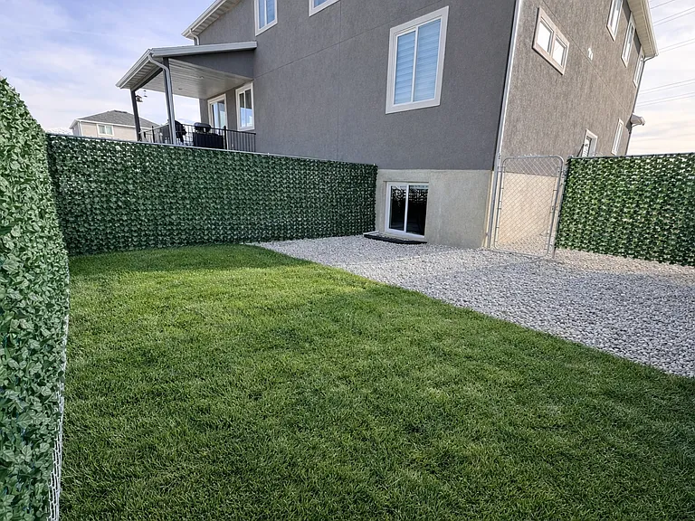 Fully fenced Spacious private backyard with fresh grass, clean gravel area, and full privacy fencing.
