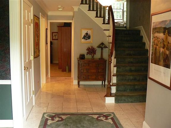 Open entrance with marble floor and curved staircase.