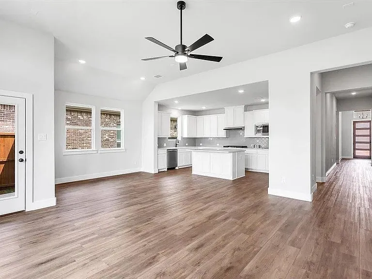 Spacious open-concept living area featuring wood-finish flooring, recessed lighting, and a modern ceiling fan