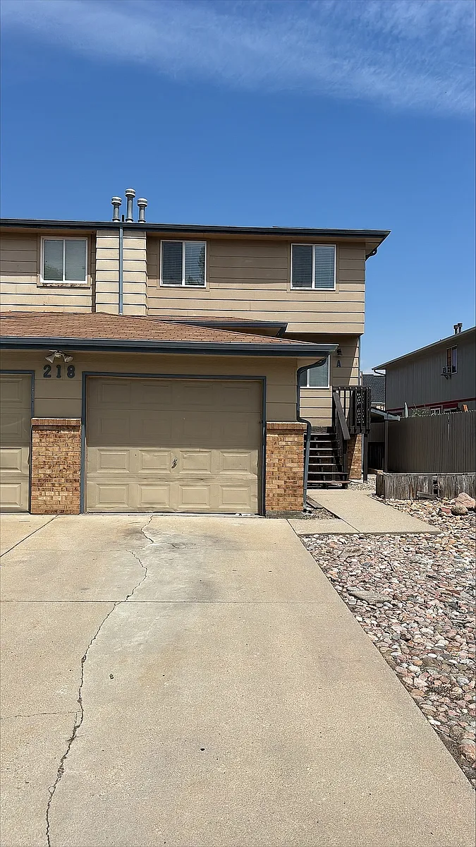 Charming two-story apartment with attached garage and inviting pathway, surrounded by a tidy rock landscape. - 208 E Longs Peak Ave