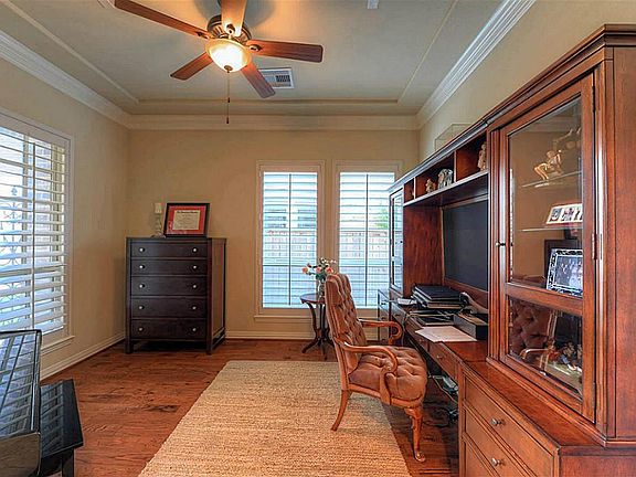 Versatile study boasts hardwood flooring, plantation shutters, French doors, crown millwork, & surro