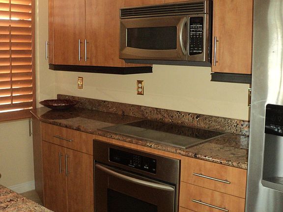 Kitchen with nice cabinetry and countertop, electric cooktop/built in oven, dishwasher, refrigerator and microwave & tile floor