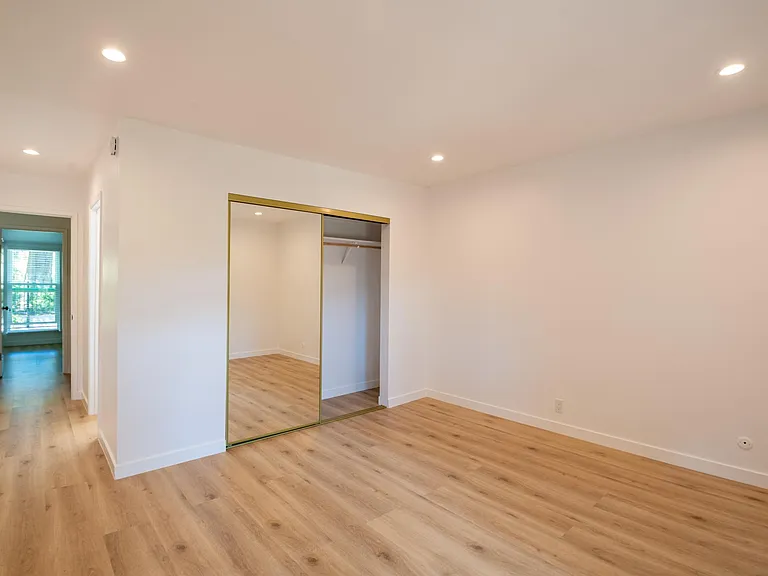 Corner view of the primary bedroom suite showing its private hallway and entrance, full wall closet, and en suite bathroom to left of entrance.