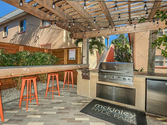 Inviting outdoor patio with stylish pergola, bar seating, and modern grill, ideal for entertaining in a lush garden setting.