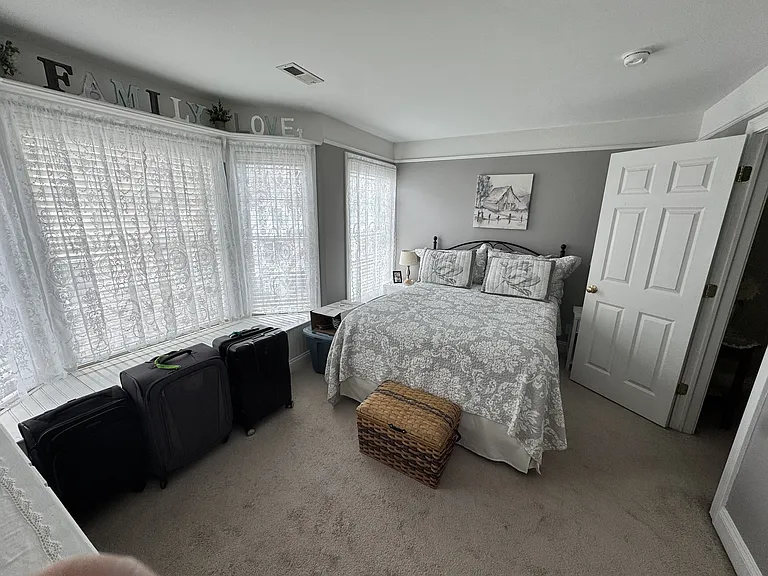 Sun filled bedroom with lots of windows, built in window seat with storage, upper shelves and picture frame molding.