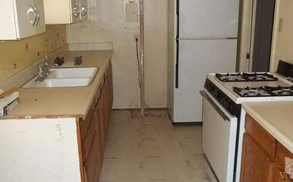 Kitchen has damaged flooring, countertops, walls & wood cabinets have damaged finish.  Stove & refrigerator will remain without warranty. Upper cabinetry is metal.