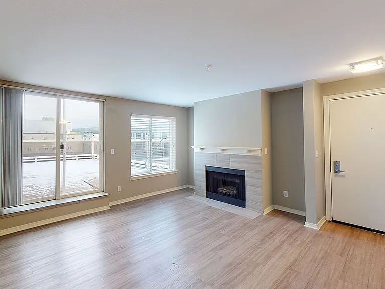 Apartment living room with wood-style flooring and fireplace in select homes.