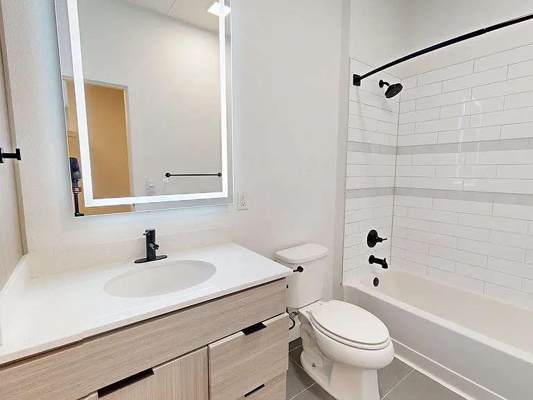 Apartment Bathroom with LED vanity mirror and Tile Floor.