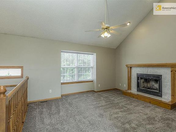 Lots of light in this living room with a fan and fireplace.
