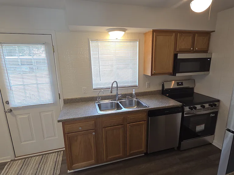 Brand-new stainless-steel refrigerator, range, microwave, and dishwasher.