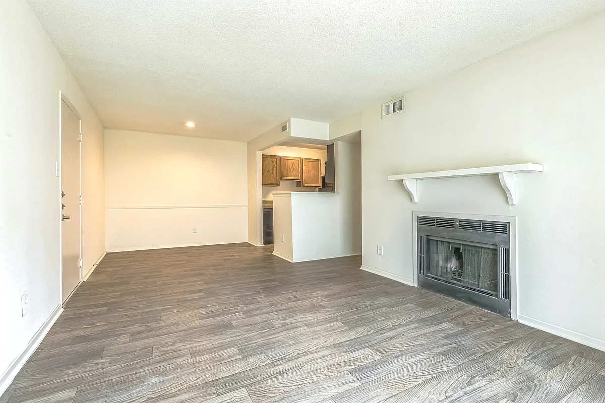 Enjoy cozy evenings by the fireplace in spacious living areas featuring beautiful wood flooring, professionally operated by Highlands Vista Group. - Ashford Place