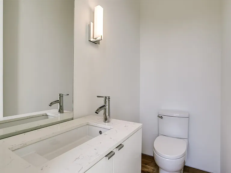 Powder room featuring a sleek white vanity with a rectangular undermount sink, a polished chrome faucet, and a large wall-mounted mirror