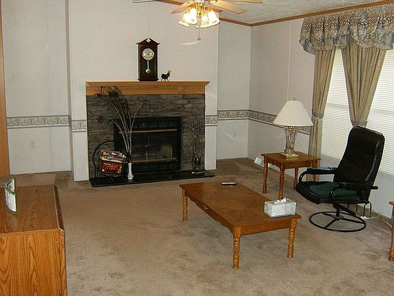 Living room comes with prefab fireplace, raised ceiling, and ceiling fan.