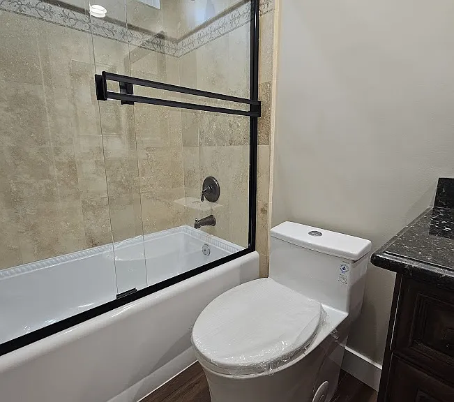 New low-water-usage skirted toilet, and new shower doors complement the granite countertop