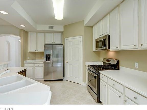 White corian countertops with new stainless steel appliances.  Walk in pantry.