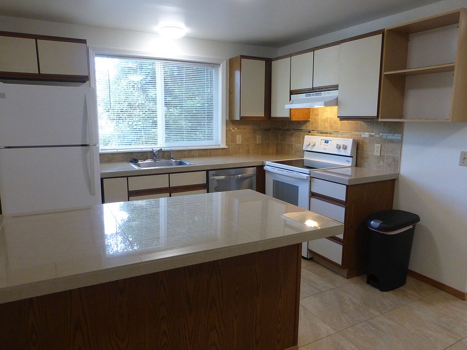 Bright kitchen with window at sink has newer fridge, dishwasher and glass-top stove.